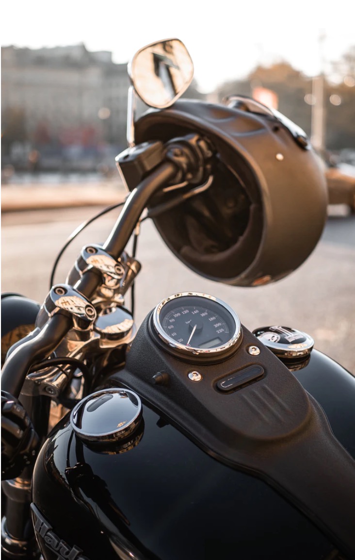 Black motorcycle picturing dash with helmet on the handle bar